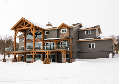 Backyard view of timber framed home, including wrap around covered patio.