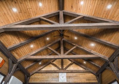 Timberframed ceiling with ceiling fan and wall clock.