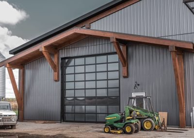 Full view of a timber frame detail on a farm shop with garden tractors out front.